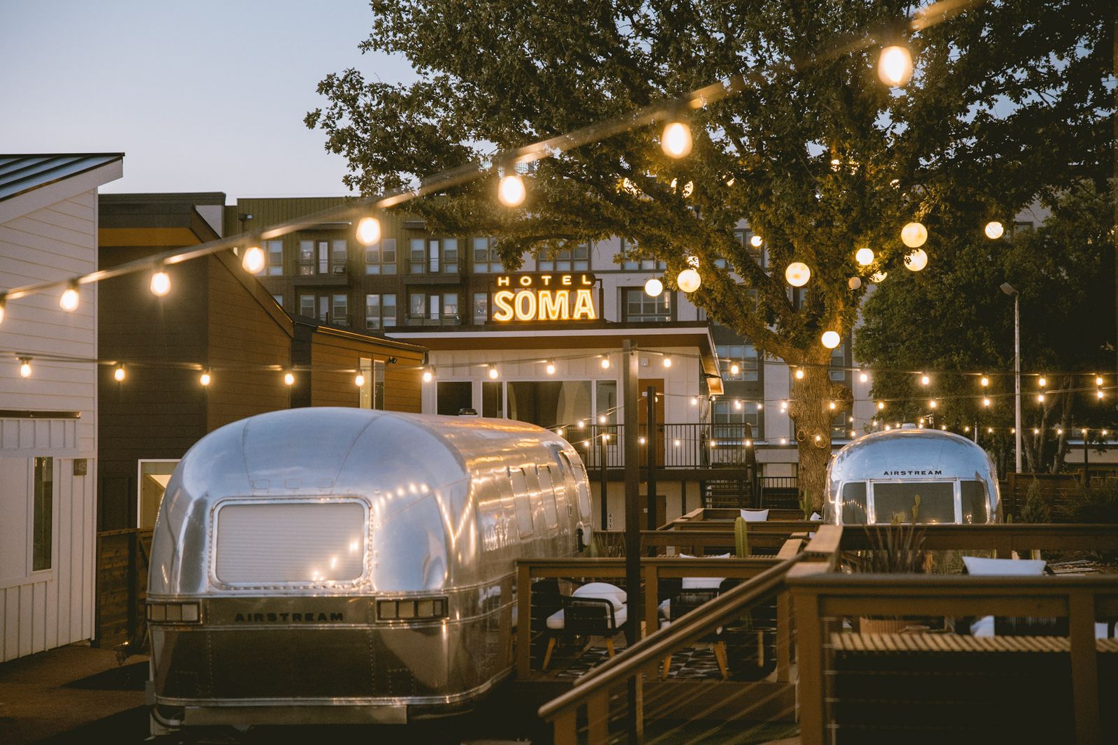 Airstream suites under string lights at dusk in the gated Hotel SOMA courtyard