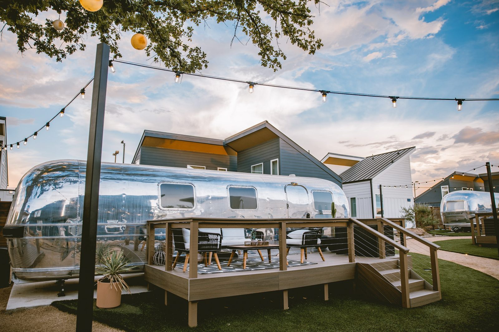 Custom Airstream suite on its own private wood deck in the Hotel SOMA courtyard in Fort Worth, under string lights and blue sky